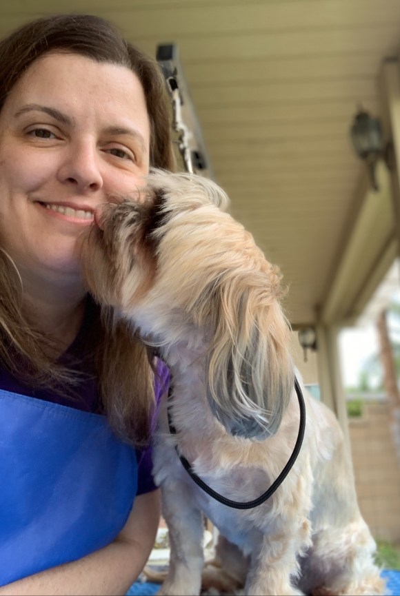 Valley Paw Spa owner receives a kiss from a small tan dog after a full service groom in Murrieta, CA